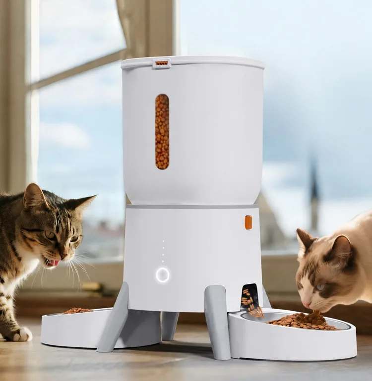Two cats eating from the double bowls of an automatic pet feeder