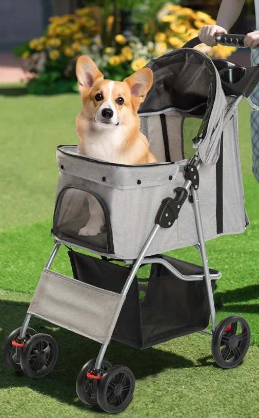 Corgi riding in a grey foldable pet stroller on grass