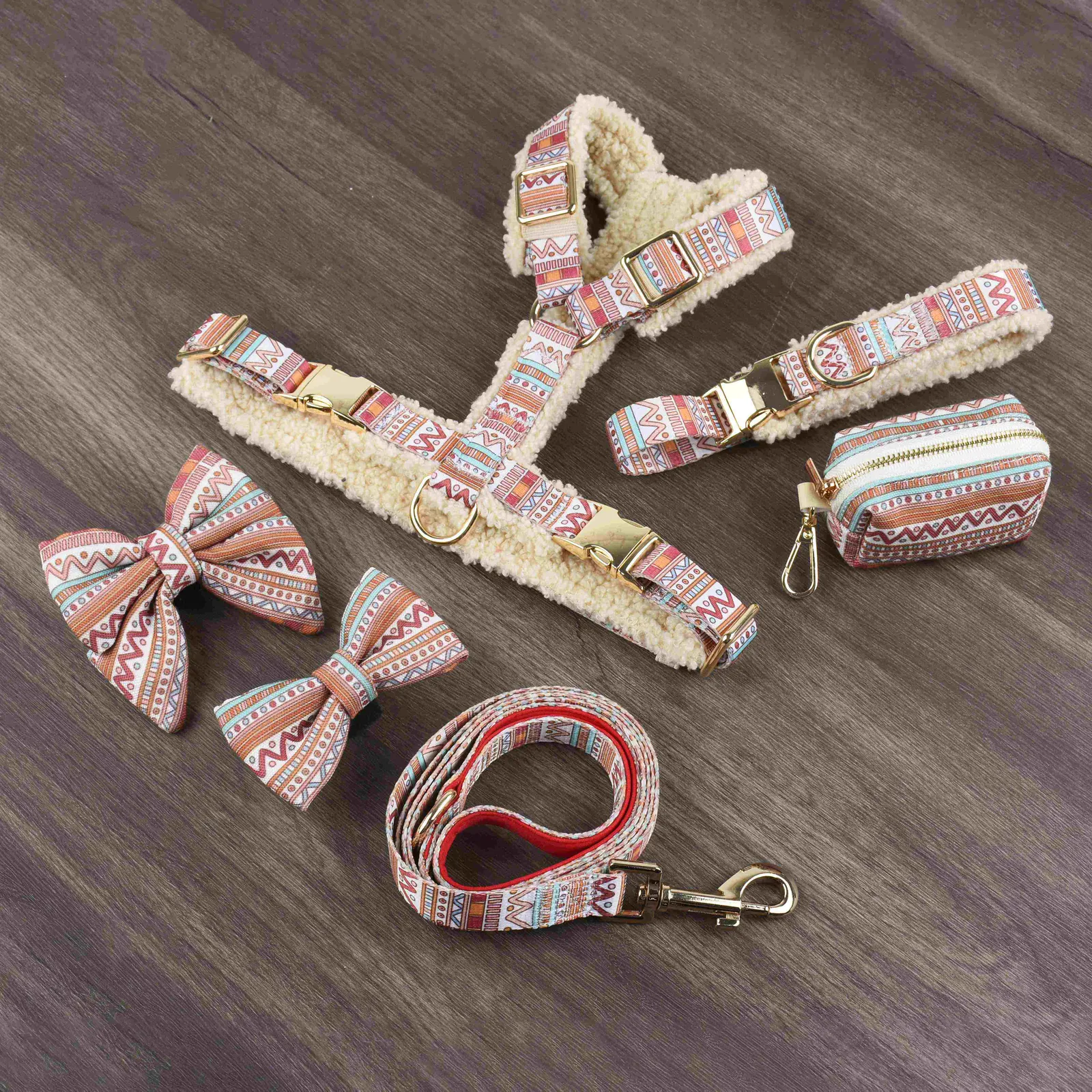 Cream teddy fleece dog harness set laid flat on wood, with collar, waste-bag holder and patterned bow ties